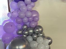 A cluster of purple, silver, and white balloons arranged decoratively.